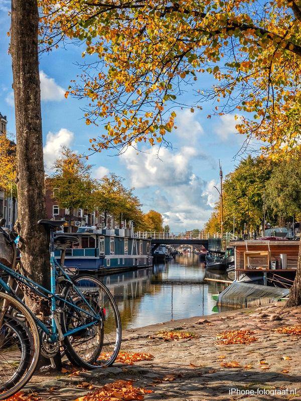 This iPhone photo of Groningen was made in Groningen. There is a bicycle in the foreground and a canal with houseboats in the background.