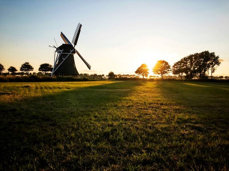 Photograph landscapes with your iPhone during the golden hour. On this photo you can see a mill and its long shadows. Sunset.